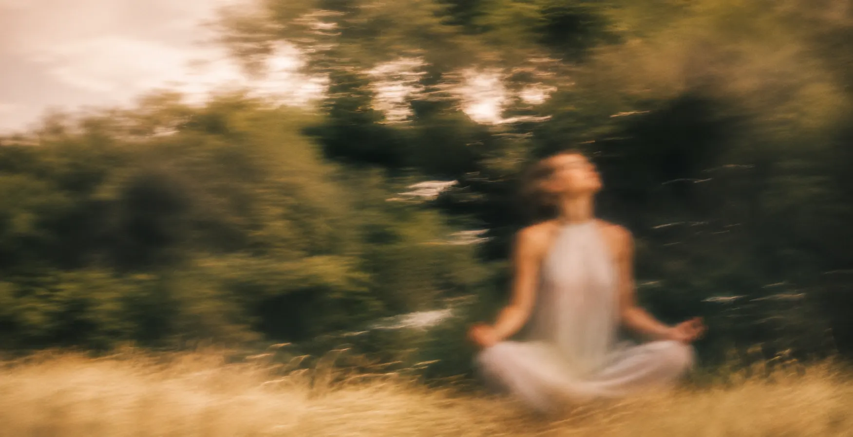 a woman meditating alone in golden grass, motion blur
